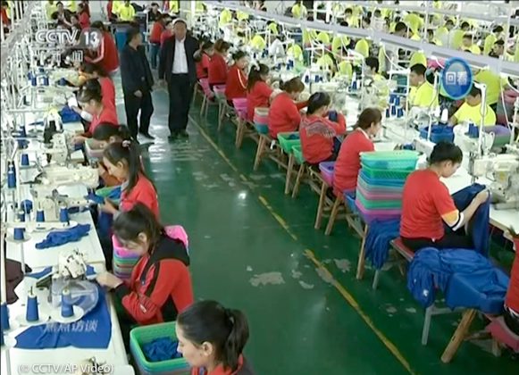 في هذا الصورة غير المؤرخة، يعمل المتدربون المسلمون في مصنع للملابس في مركز هوتان للتعليم والتدريب المهني في شينجيانغ