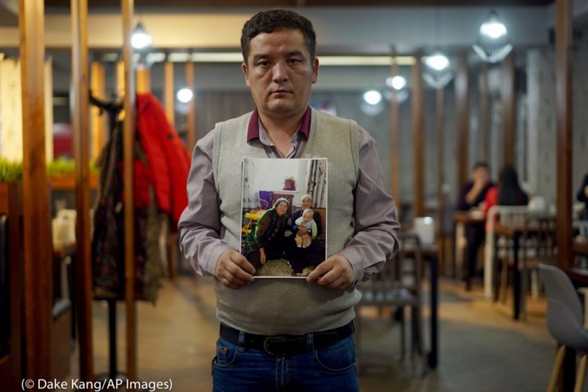 مهاجر صيني المولد في كازاخستان يحمل صورة لعائلته في العام 2018. يقول إن والده تم إجباره على العمل في مصنع بمنطقة شينجيانغ الصينية